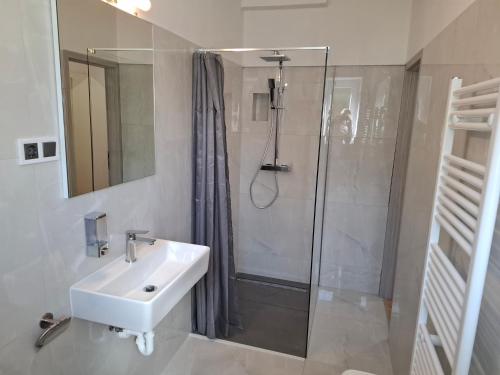 ein weißes Bad mit einem Waschbecken und einer Dusche in der Unterkunft Barka Zadar in Zadar