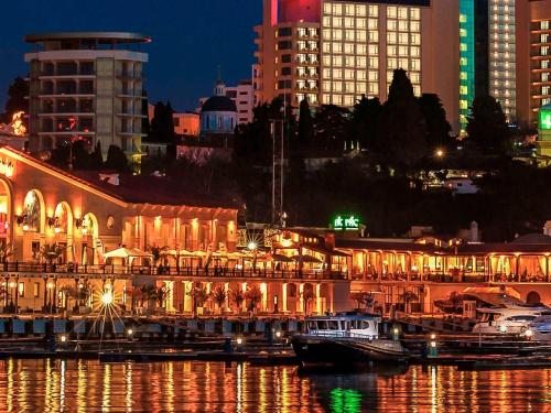 a city lit up at night with boats in the water at Mercure Sochi Centre Hotel in Sochi