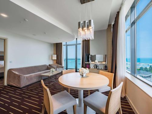 een woonkamer met een tafel en stoelen en een bank bij Mercure Sochi Centre Hotel in Sotsji