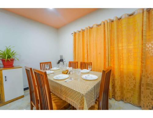 uma sala de jantar com uma mesa com cadeiras e cortinas cor de laranja em Sunshine villa panchgani 5 bedrooms villa em Panchgani