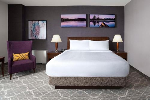 a bedroom with a large bed and a purple chair at Hilton Garden Inn Calgary Airport in Calgary