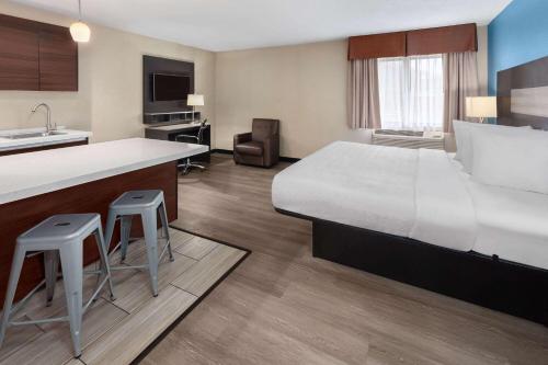 a hotel room with a large bed and a kitchen at Baymont by Wyndham Copley Akron in Copley