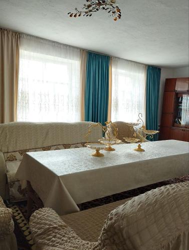 a room with a table and a couch and windows at Guest House Bereke in Kyzart village in Bagysh