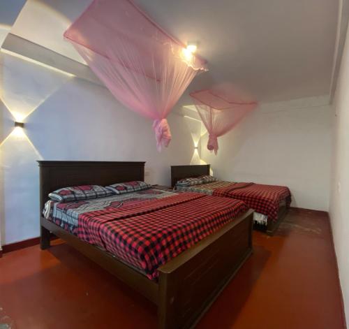 a bedroom with two beds with mosquito nets on the wall at Blue Sky Guest House And Restaurant in Nallathaniya