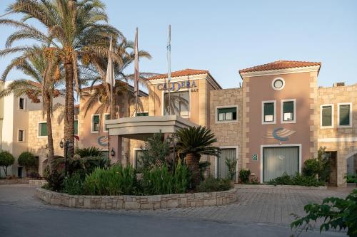 a building with palm trees in front of it at Caldera Bay in Plataniás