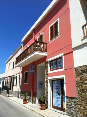 a red and white building on the side of a street at Al Martin Pescatore in Stintino