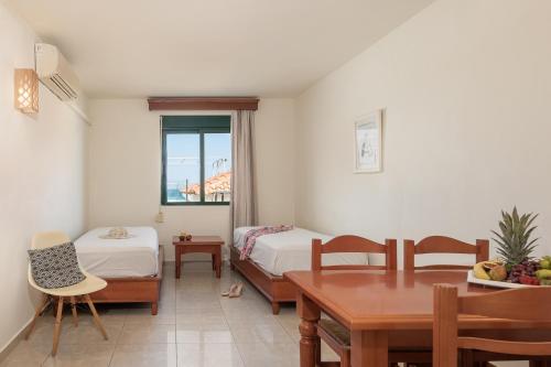 a room with two beds and a table and chairs at Caldera Bay in Platanias