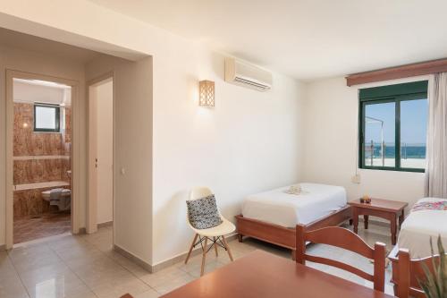 a bedroom with a bed and a table and a chair at Caldera Bay in Plataniás