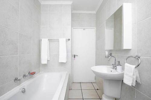 y baño blanco con lavabo, bañera y lavamanos. en Beautiful 2 bedroom apartment!, en Sandown