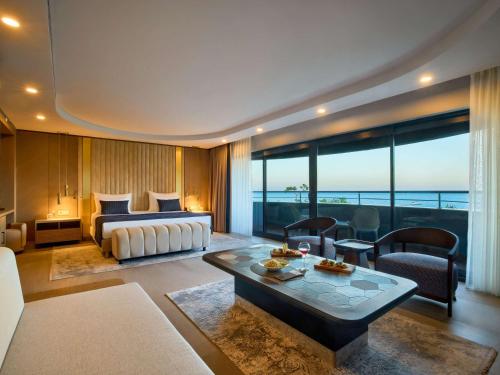 ein Hotelzimmer mit einem Bett und einem Wohnzimmer in der Unterkunft Movenpick Resort Antalya Tekirova in Tekirova
