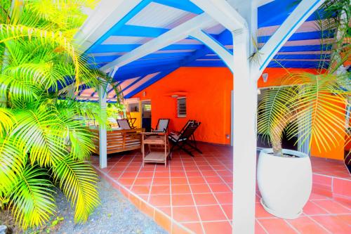 a patio with an orange and blue ceiling and palm trees at Nature Paradise Pool & Spa - Exceptional Secluded Luxury Location in Le Diamant