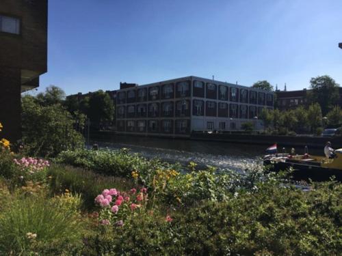 ein Gebäude neben einem Fluss mit Blumen in der Unterkunft Westerpark Loft, private studio in Amsterdam