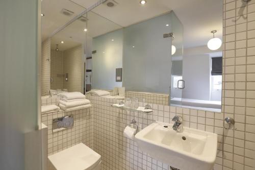 uma casa de banho com um lavatório, um WC e um espelho. em Prince William Hotel em Londres