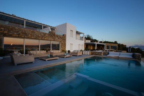 une piscine avec des canapés et une maison dans l'établissement Amaris Mykonian Residence, à Ornos