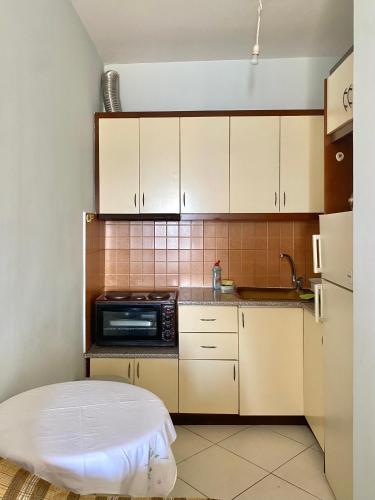 una piccola cucina con mobili bianchi e un forno a microonde di Caramel Sun Studios Apts a Sarandë