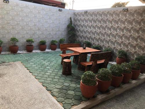 a patio with a wooden table and benches and potted plants at 3-Bedroom bungalow in San Fernando Pampanga in San Fernando