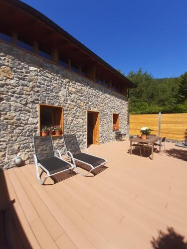 duas cadeiras sentadas num deque ao lado de um edifício de pedra em CASA RURAL AINGERU NATURALEZA Y MONTAÑA em Oñate