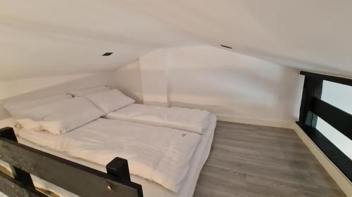 Una cama pequeña en una habitación con una pared blanca. en Dream Apartments 1B KLIMATYZACJA, en Oświęcim