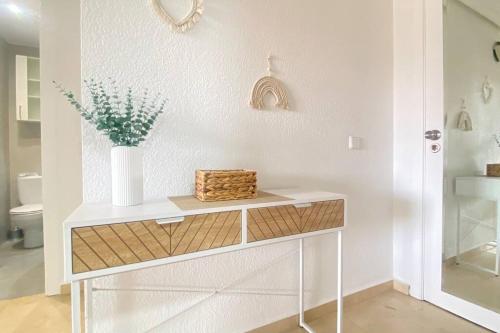 a white console table with a vase of flowers on it at Appartement Capitolio Albir 1G in Albir