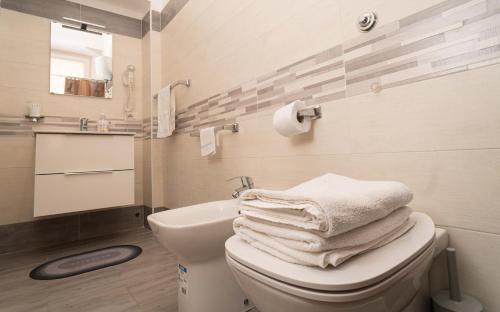 - une salle de bains avec un tas de serviettes sur les toilettes dans l'établissement Casa Vacanze Alma B&B grazioso appartamento sul lungomare di Pozzuoli a 300mt dal centro e dal Rione Terra by Movery, à Pouzzoles