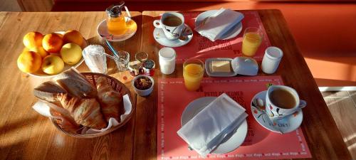 a table with breakfast foods and cups of coffee at Logis hôtels Auberge du Château in Saint-Rémy-de-Blot