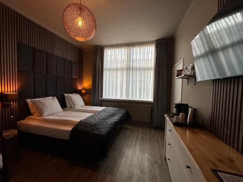 a bedroom with a bed and a large window at Hotel Buren in West-Terschelling