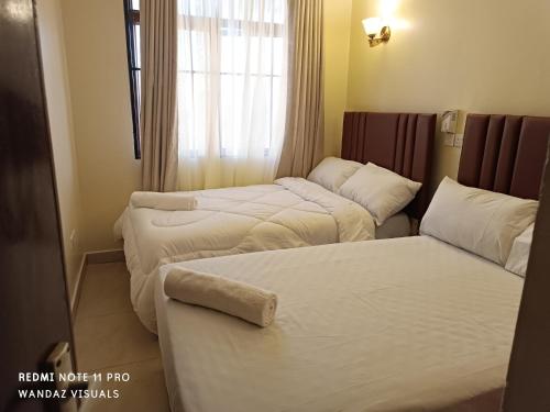 a hotel room with two beds and a window at Elegant furnished rooms with swimming pool in Nyali in Mombasa