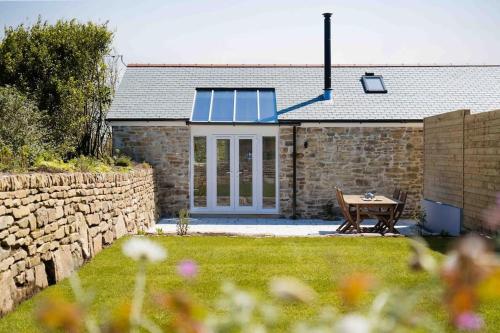 a stone house with a table in the yard at Meadow View Barn, Rural St Ives, Cornwall. Brand New 2 Bedroom Idyllic Contemporary Cottage With Log Burner. in Nancledra
