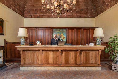 a man sitting at a desk with a laptop at Relais La Fattoria in Castel Rigone