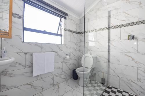 a bathroom with a toilet and a glass shower at Zuri Place in East London