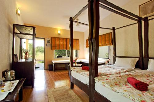 a bedroom with two canopy beds and a bathroom at Gir Birding Lodge in Sasan Gir
