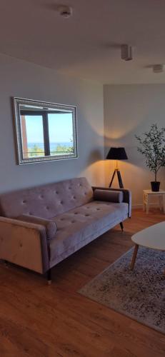 a large couch in a living room with a window at Pinea Apartments in Pobierowo
