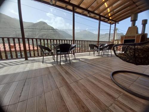 a balcony with chairs and tables and a view of mountains at Come & Rest in Stepantsminda