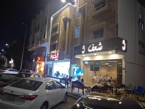 dos coches estacionados frente a un restaurante por la noche en الفاخرة, en Al Khobar