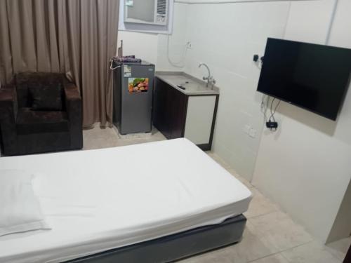 a room with a bed and a refrigerator and a tv at الفاخرة in Al Khobar