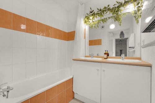 ein Badezimmer mit zwei Waschbecken, einer Badewanne und einem Spiegel in der Unterkunft Le Chapitre Toulousain - WILDHOME in Toulouse