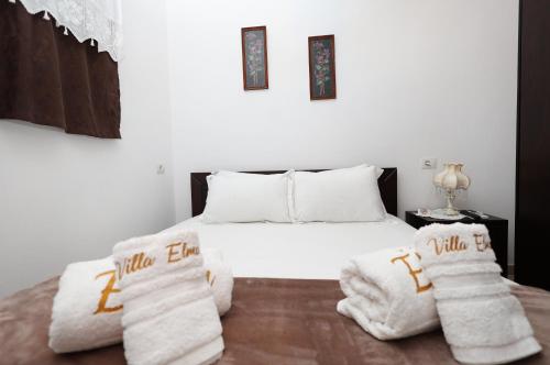 een slaapkamer met een bed met witte dekens en handdoeken bij Villa ELMAR in Berat