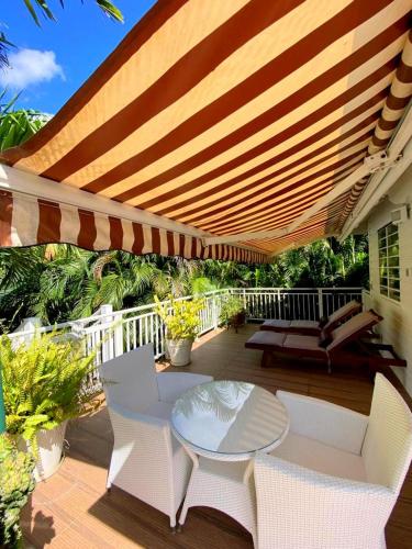 a patio with a table and chairs under a large umbrella at Nature Paradise Pool & Spa - Exceptional Secluded Luxury Location in Le Diamant