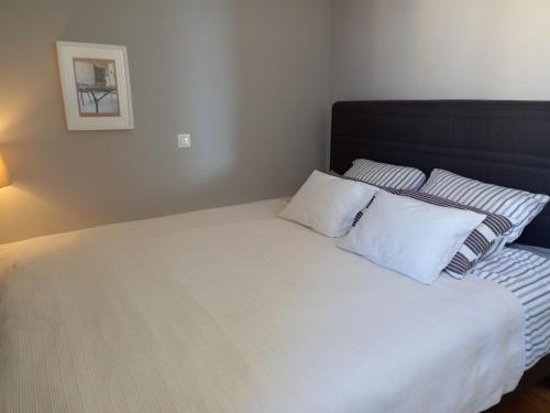 una camera da letto con letto, lenzuola e cuscini bianchi di Sea Salt Apartment a Novalja (Novaglia)