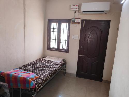 um pequeno quarto com uma cama e uma porta em AGP Castle em Chennai