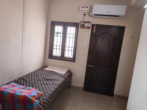 um pequeno quarto com uma cama ao lado de uma porta em AGP Castle em Chennai