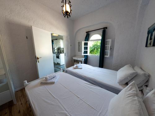 a bedroom with two white beds and a window at Tea & Sea Apts in Anissaras