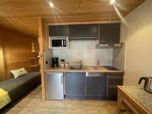 uma pequena cozinha com um lavatório e um sofá num quarto em Aravis Locations em Le Grand-Bornand