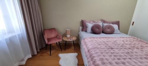 ein Schlafzimmer mit einem Bett mit einer rosa Bettdecke und einem Stuhl in der Unterkunft Silbernagel Villa apartment in Kuressaare