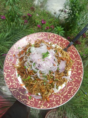 a plate of food with noodles and onions at Shoolin Cottages & Camp's in Kasol