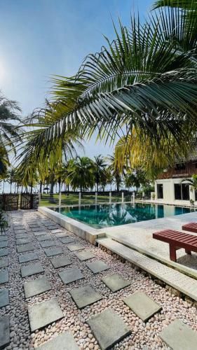 a resort swimming pool with a picnic table and palm trees at Anugerah Surf & Dive in Nembrala