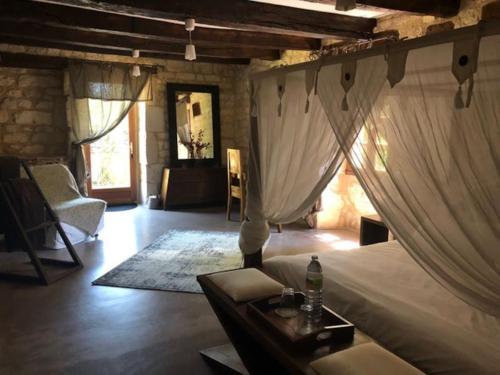a bedroom with a bed with curtains and a chair at Demeure de Charme La Source in Cestayrols