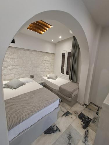 a bedroom with two beds and a stone wall at Katerina Roza Studios - Heartfelt Hospitality in the City in Naxos Chora