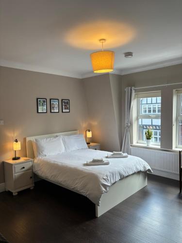 um quarto com uma cama branca e uma janela em Large West Side Room above G Grace & Son em Tring