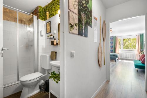 a white bathroom with a toilet and a shower at Urban Jungle Studio Apartment in Offenbach